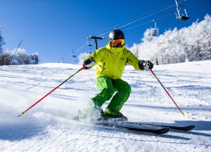 skiier wearing bright green and slaloming in front of camera at Plattekill Mountain Ski Resort